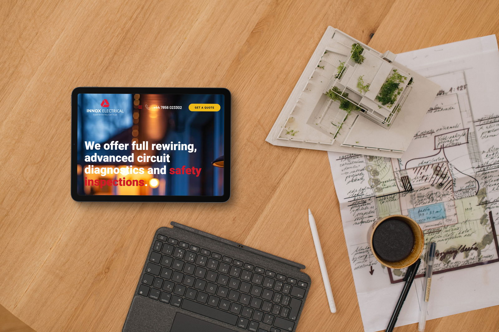 Tablet website design for Innox shown with architect plans and coffee cup